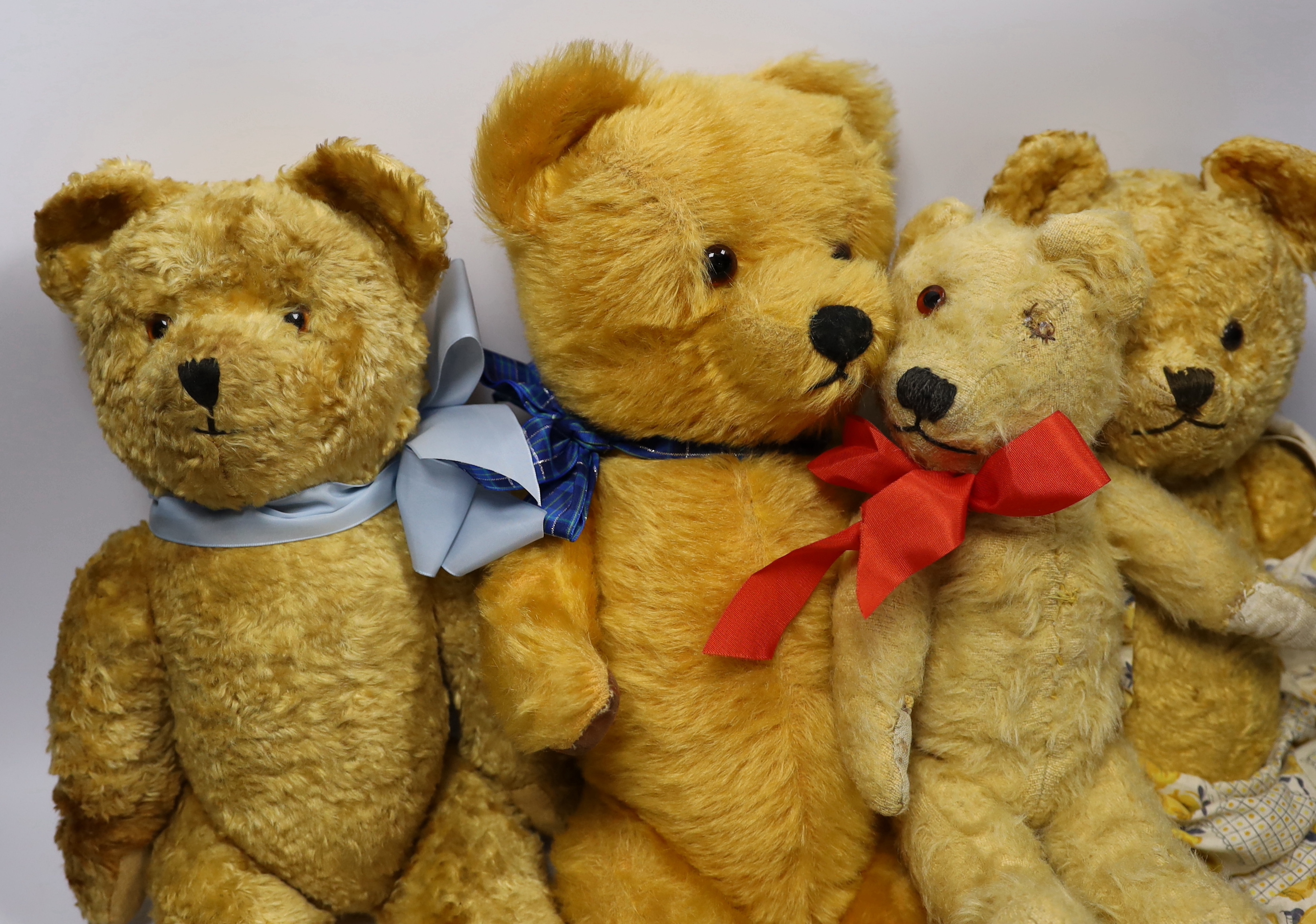 A golden plush bear with pale blue ribbon, 38cm, together with three others (4)